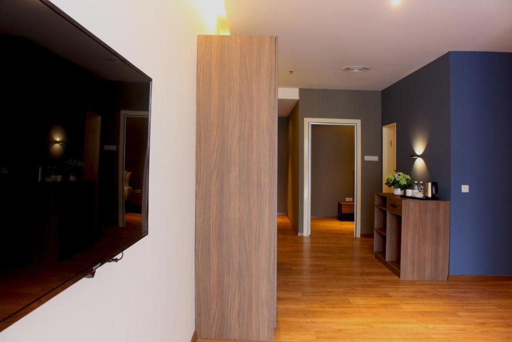 A suite interior looking past a wardrobe toward the entry, with a television at left.