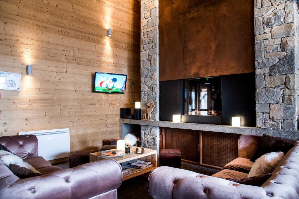 a living room with leather furniture and a stone wall at Résidence - Les Grandes Alpes in La Clusaz