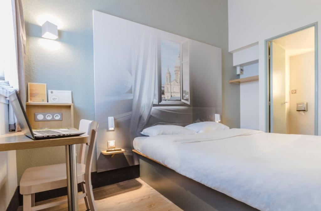 a bedroom with a bed and a desk with a laptop at B&B HOTEL Boulogne Sur Mer in Saint-Martin-Boulogne