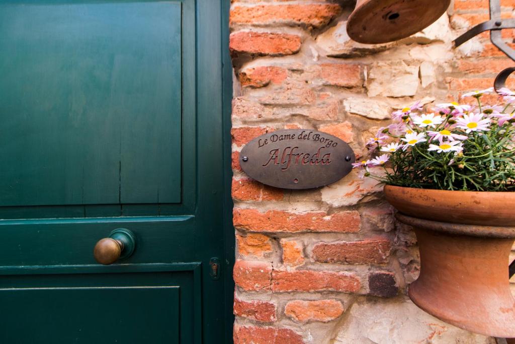 a green door and a pot of flowers next to a brick wall at Le Dame del Borgo in Sassetta