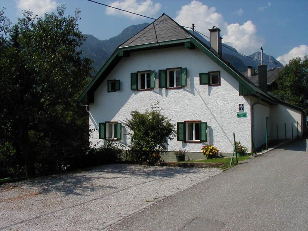 a white house with green shuttered windows on a street at Ferienhaus-Loidl in Bad Ischl
