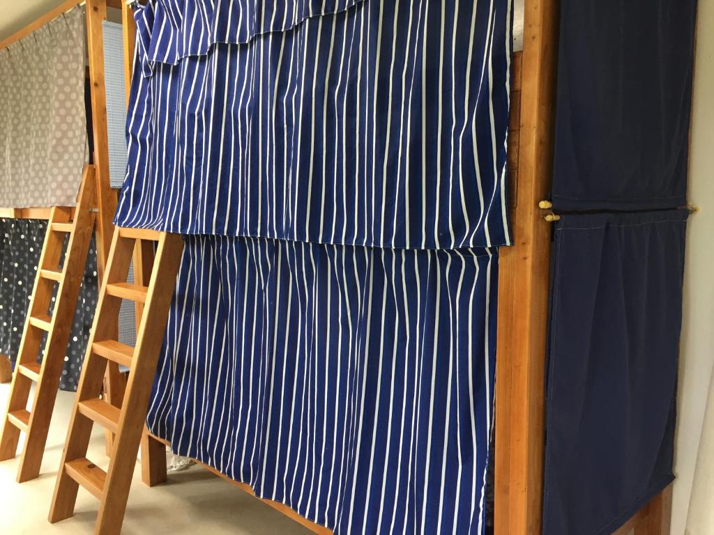 a bed with blue and white sheets and a ladder at Shimaotoya in Iriomote