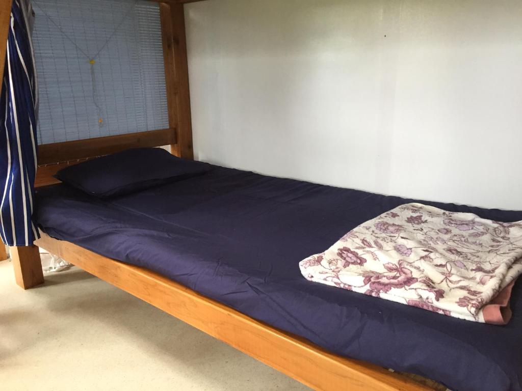 a bed in a room with a blue blanket on it at Shimaotoya in Iriomote