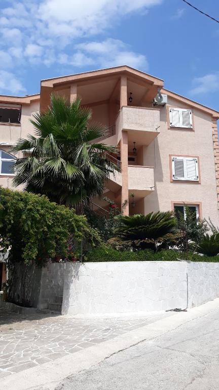 a building with a palm tree in front of it at Apartmani Tanja in Tivat