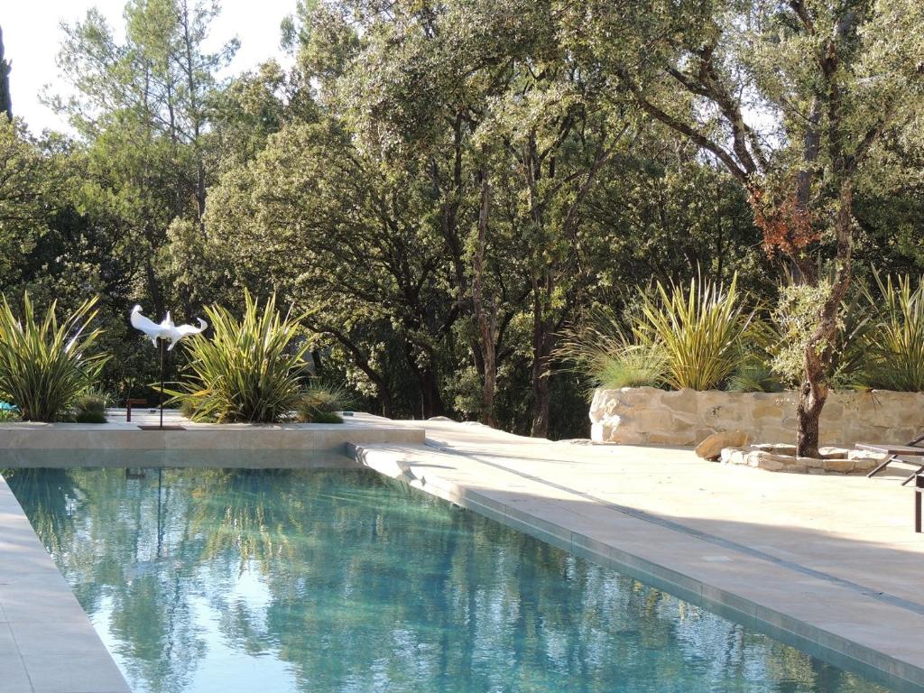 a swimming pool in a yard with trees and a bird flying over it at La Villa Kallisté in Vacquières