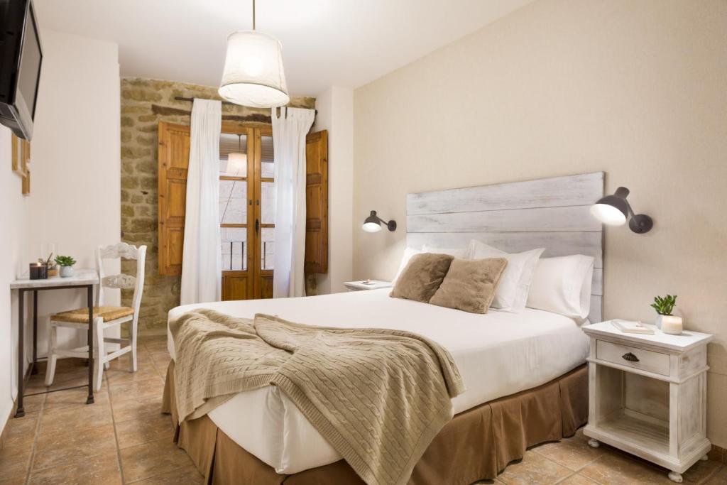 Un dormitorio con una gran cama blanca y una mesa en Posada de Uncastillo en Uncastillo