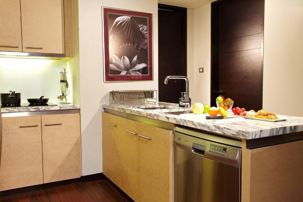 A compact apartment kitchen with a marble-topped island, sink, dishwasher and cooking counter.