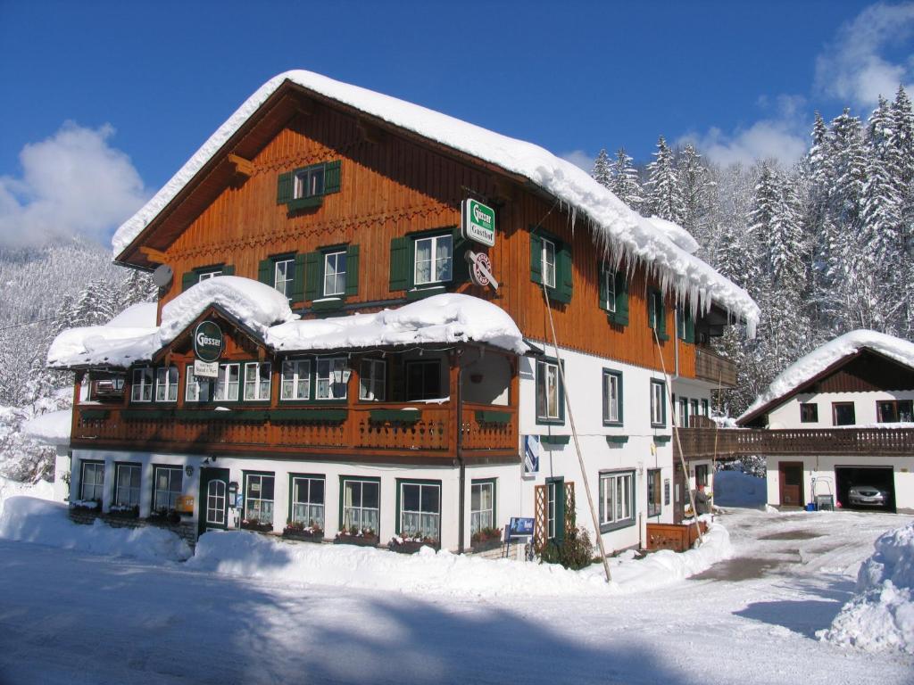 un grand bâtiment avec de la neige au-dessus dans l'établissement Gasthof Staud'nwirt, à Bad Aussee