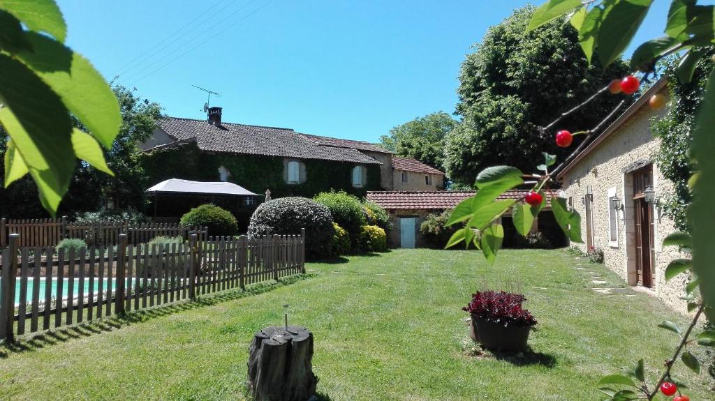 un patio con una valla y una casa en La Croisée Verte en Veyrines-de-Vergt