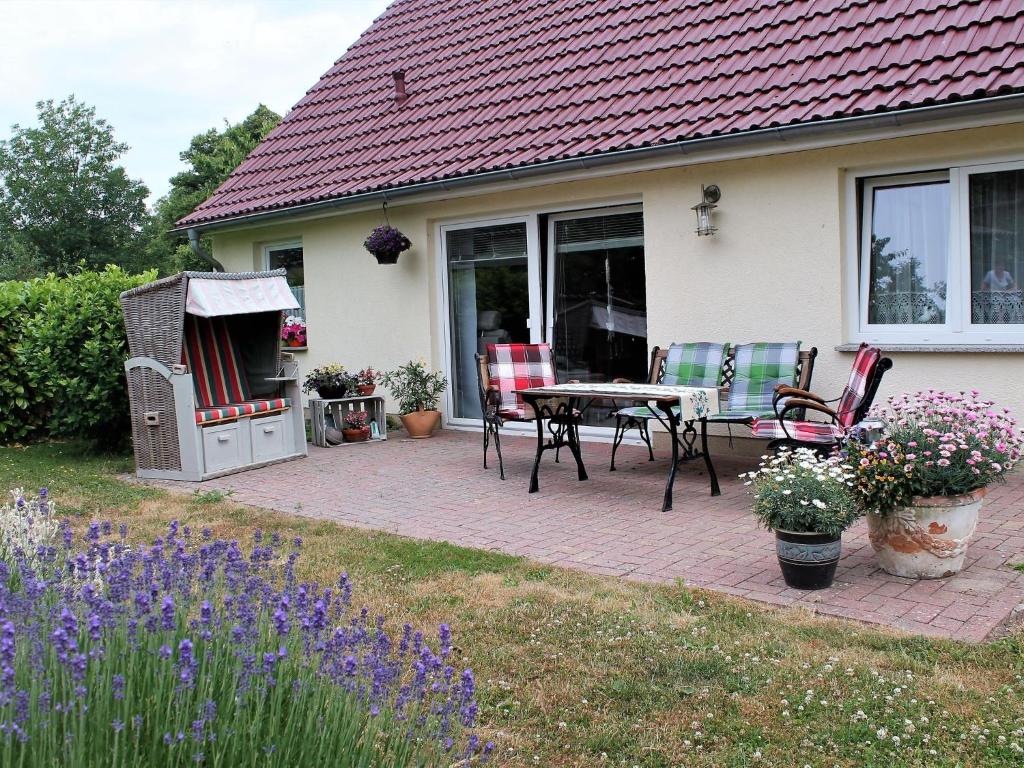 a patio with a table and chairs in front of a house at Cozy Holiday Home in Hohenkirchen near Baltic Sea in Hohenkirchen