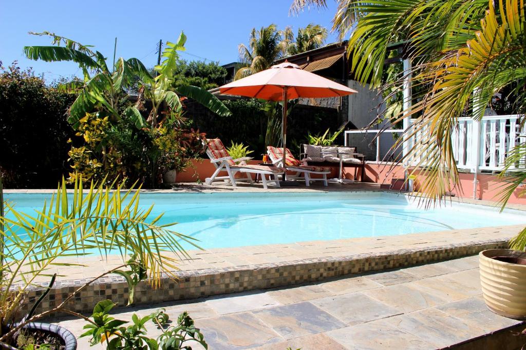 a swimming pool with a table and an umbrella at Bellevue Tamarin in Tamarin