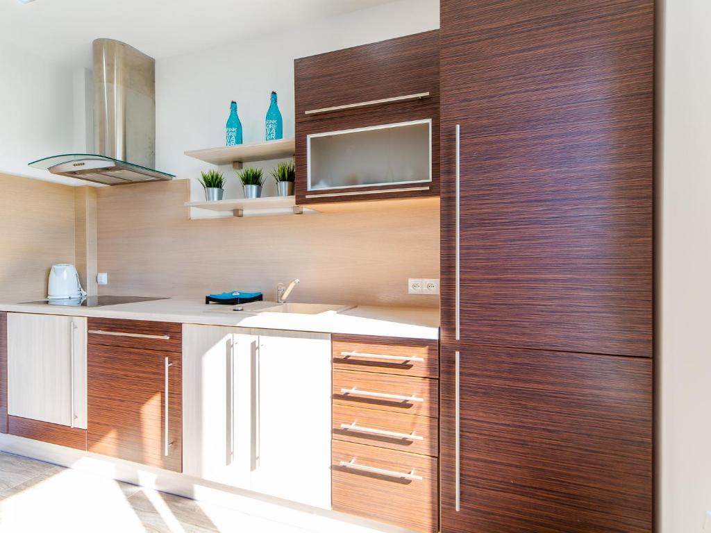 a kitchen with wooden cabinets and a refrigerator at M&M Apartamenty in Kołobrzeg