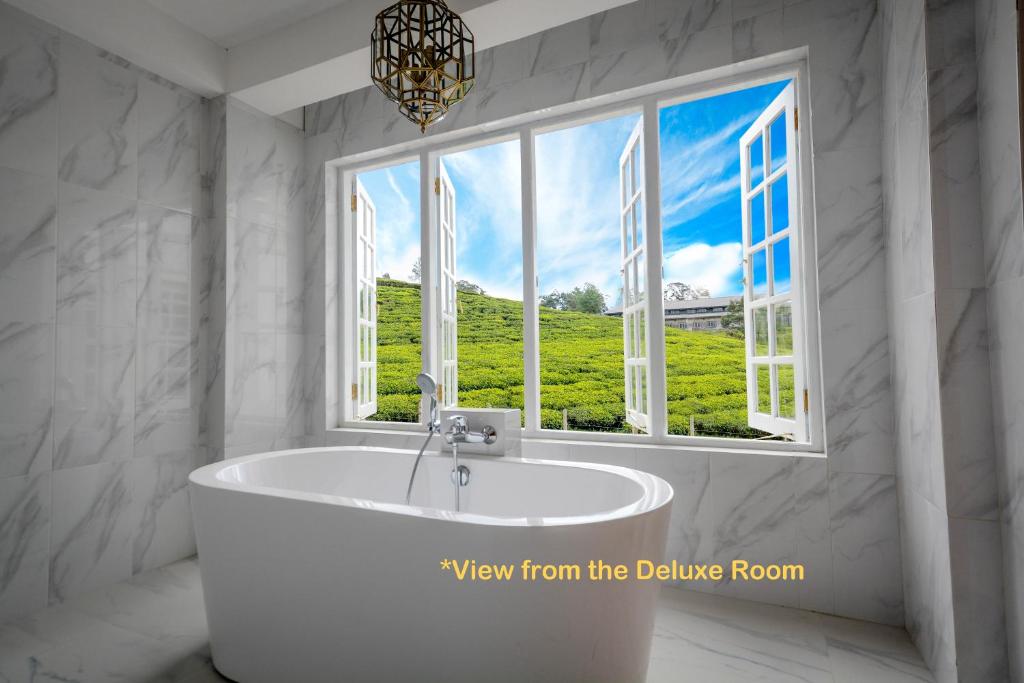 a bathroom with a bath tub in front of a window at Villa Tea Fields in Nuwara Eliya