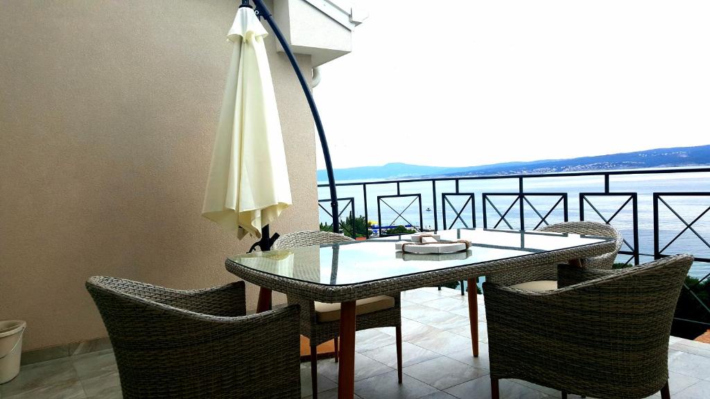 a table with chairs and an umbrella on a balcony at Apartments Villa Harmonie - Adults Only +14 in Crikvenica