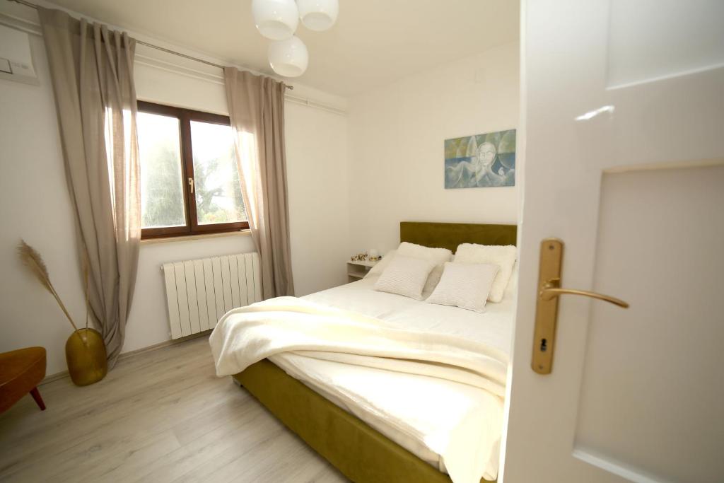 una camera da letto con un letto con lenzuola bianche e una finestra di Garden a Pola (Pula)