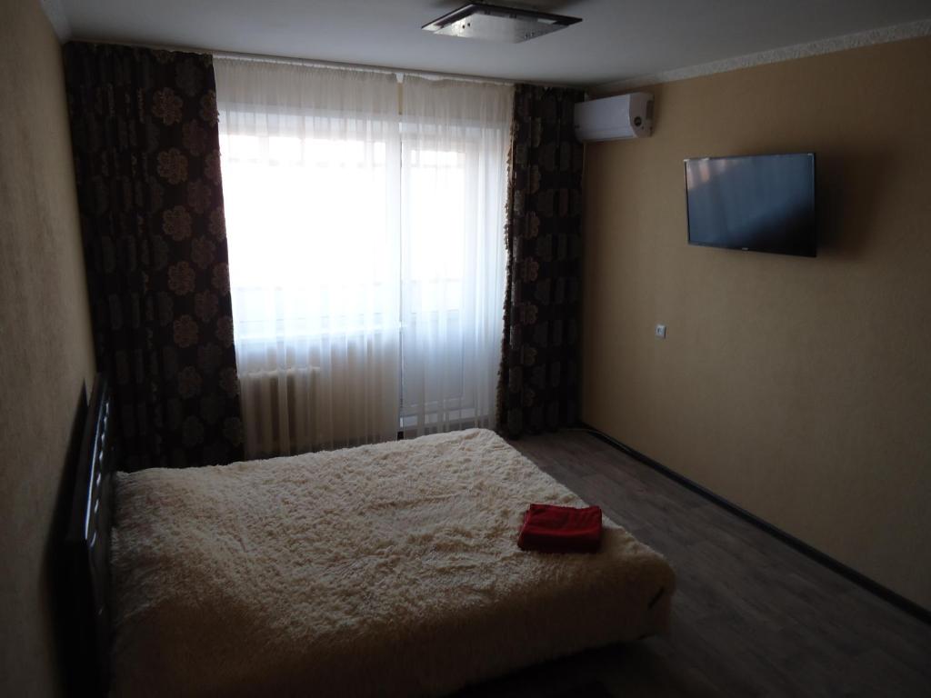 um quarto com uma cama e uma janela com uma televisão em Apartment on Leningradskaya 7 em Volgodonsk