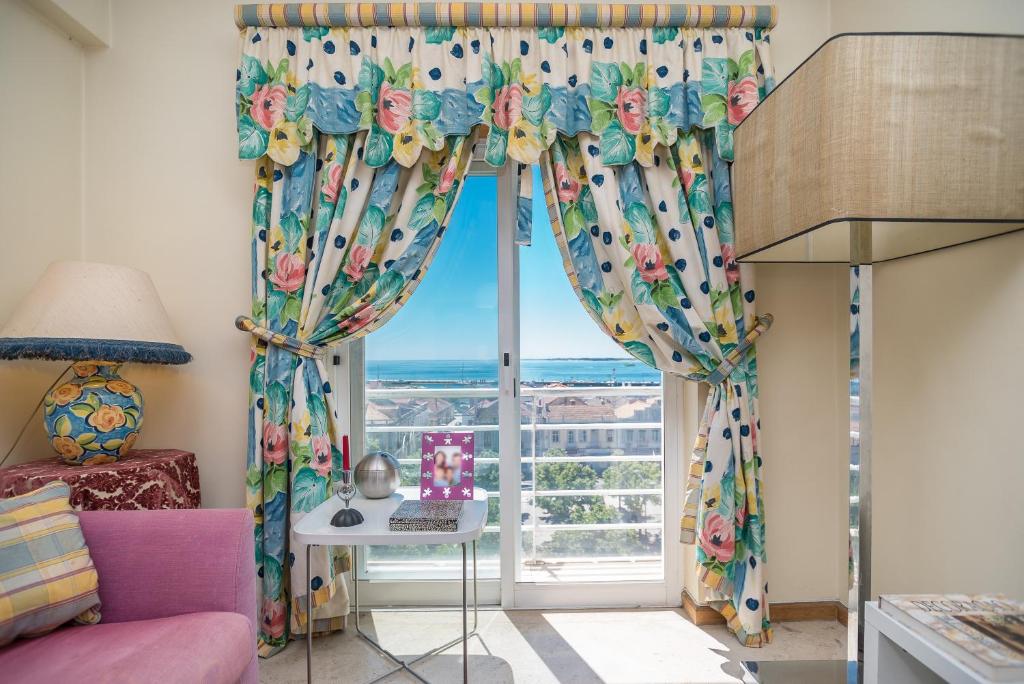 a room with a window with curtains and a table with a laptop at Setubal Dreams in Setúbal