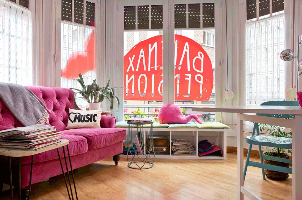 a living room with a pink couch in front of windows at Balenax Pensión in Gijón