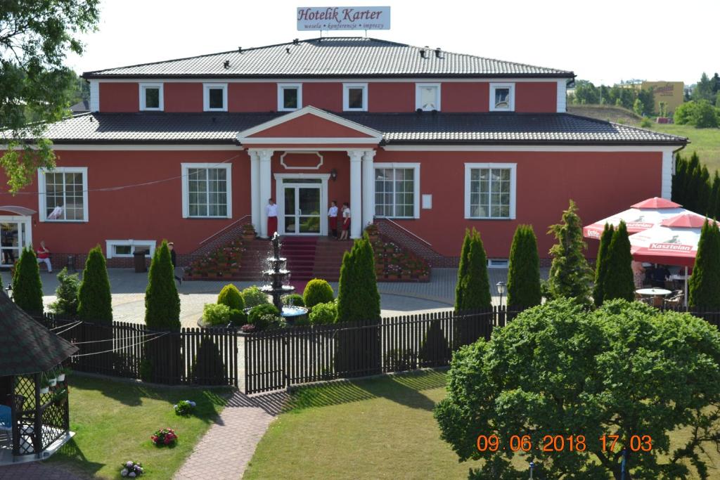 a red house with a fence in front of it at Hotelik Karter in Warsaw