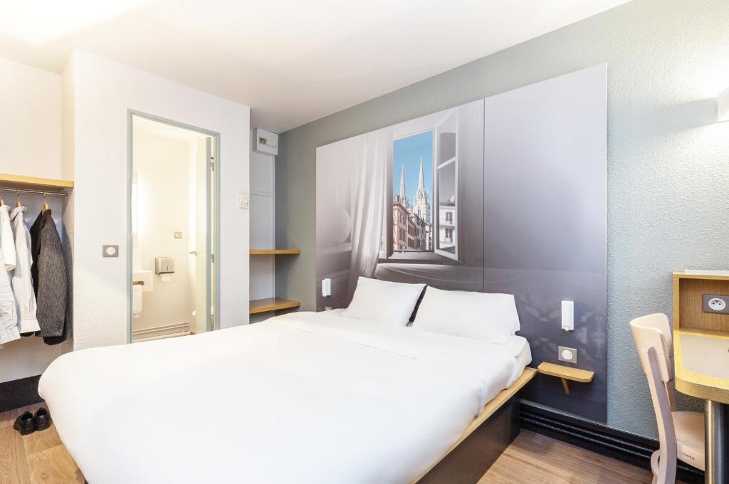 - une chambre avec un grand lit blanc et un bureau dans l'établissement B&B HOTEL Bayonne, à Bayonne