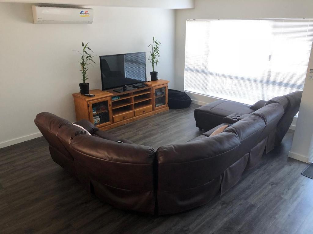 uma sala de estar com um sofá de couro e uma televisão de ecrã plano em Falcon Bay 4x4 Townhouse em Wannanup