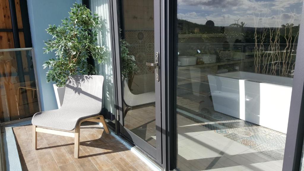 a white chair sitting on a balcony next to a sliding glass door at 湛藍海岸民宿 Azure--這個夏天有點藍--墾丁南灣沙灘-可包棟-國旅卡特約店 in Nanwan