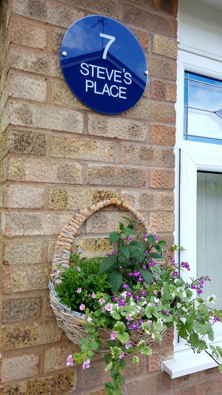 a sign on a brick wall with a basket of flowers at Steve's Place in Stoney Stanton