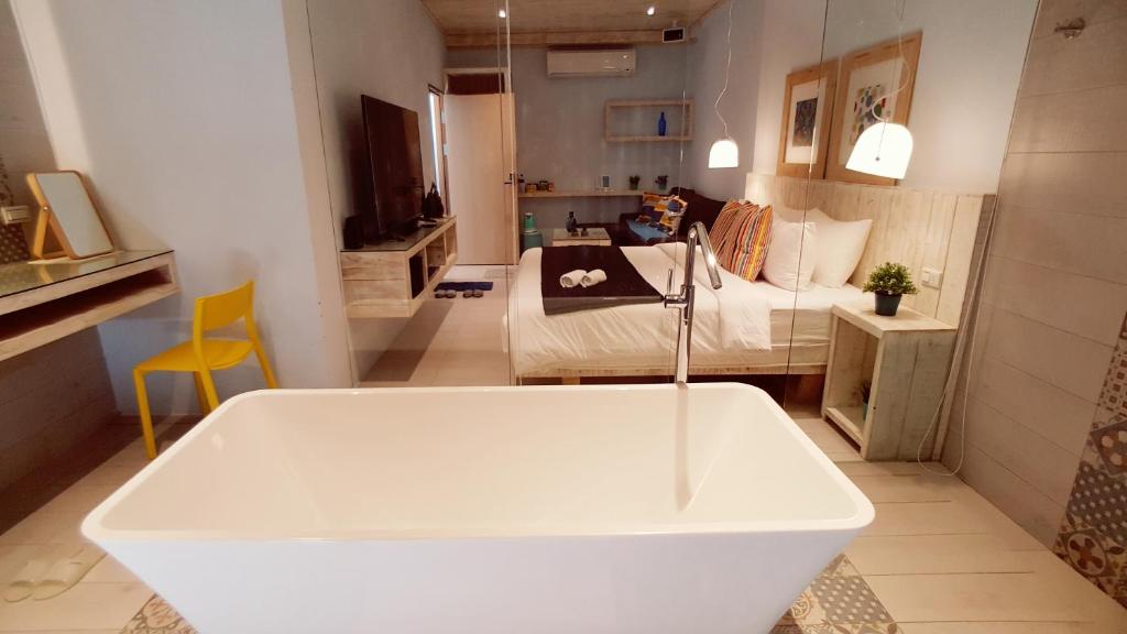 a white bath tub in a room with a bed at 湛藍海岸民宿 Azure--這個夏天有點藍--墾丁南灣沙灘-可包棟-國旅卡特約店 in Nanwan