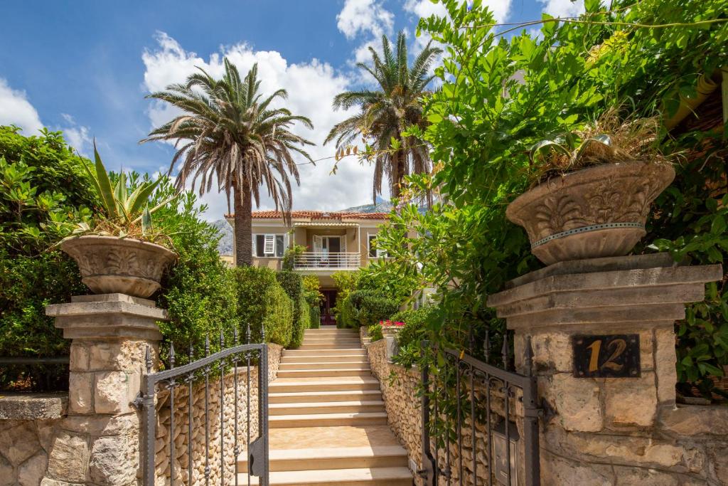 a gate leading to a house with palm trees at Vila Niko in Makarska