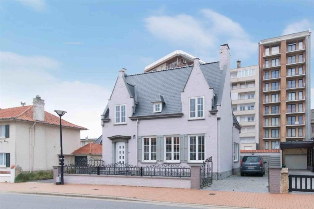 a white house in front of a building at Rust op de Kust - Villa 10 pers - 4 slpk - 2 badk in Middelkerke