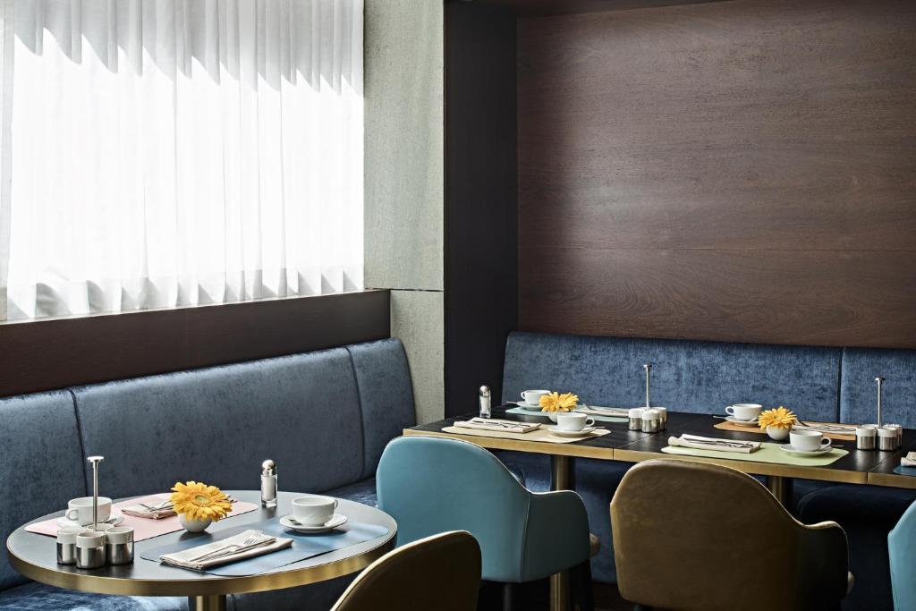 a dining room with two tables and blue chairs at SIDE, Hamburg, a Member of Design Hotels in Hamburg