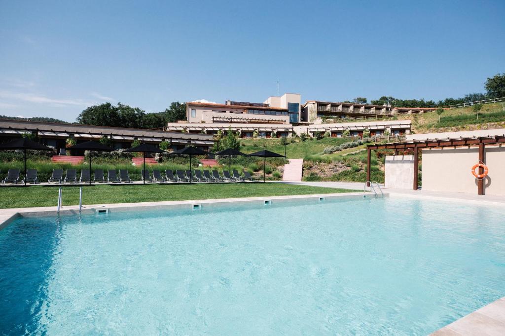 ein großer blauer Pool mit einem Gebäude im Hintergrund in der Unterkunft Mas Salagros EcoResort & SPA in Vallromanas