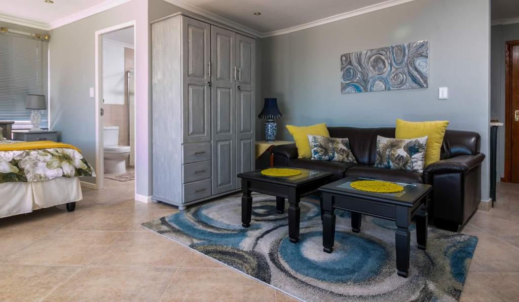 a living room with a couch and two tables at Gordon's Bay Guesthouse in Gordonʼs Bay