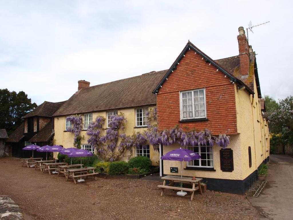 un bâtiment avec des parapluies et des bancs violets devant lui dans l'établissement Red Lion, à Exeter