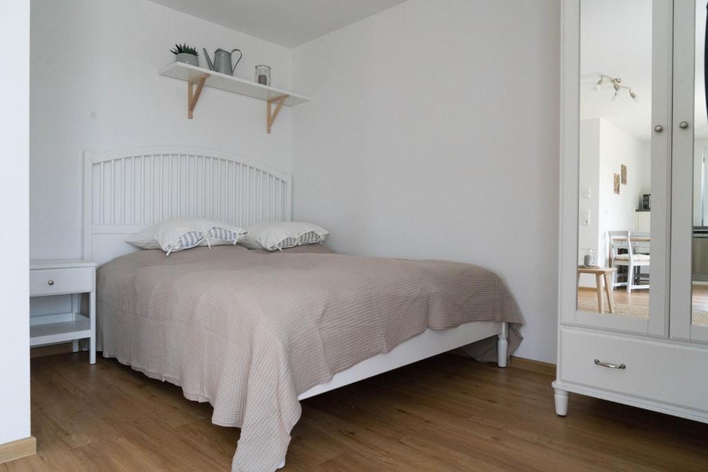 a white bedroom with a bed and a mirror at Apartment Schneeburg in Ebringen