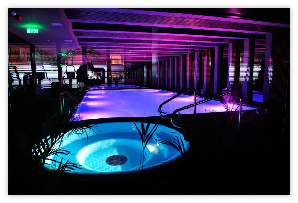 a swimming pool with purple lights next to a building at Luxury Downtown Apartments in Budapest