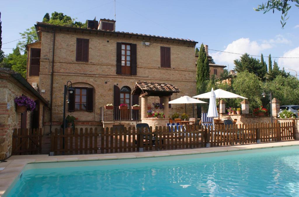 a house with a fence next to a swimming pool at Casa Vacanze L'Oliveta in Siena