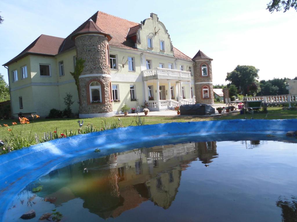 a large house with a reflection in a pool of water at Gutshaus Darsikow in Darsikow