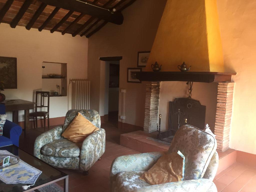 sala de estar con 2 sillas y chimenea en Podere Gnocchi, en Rapale