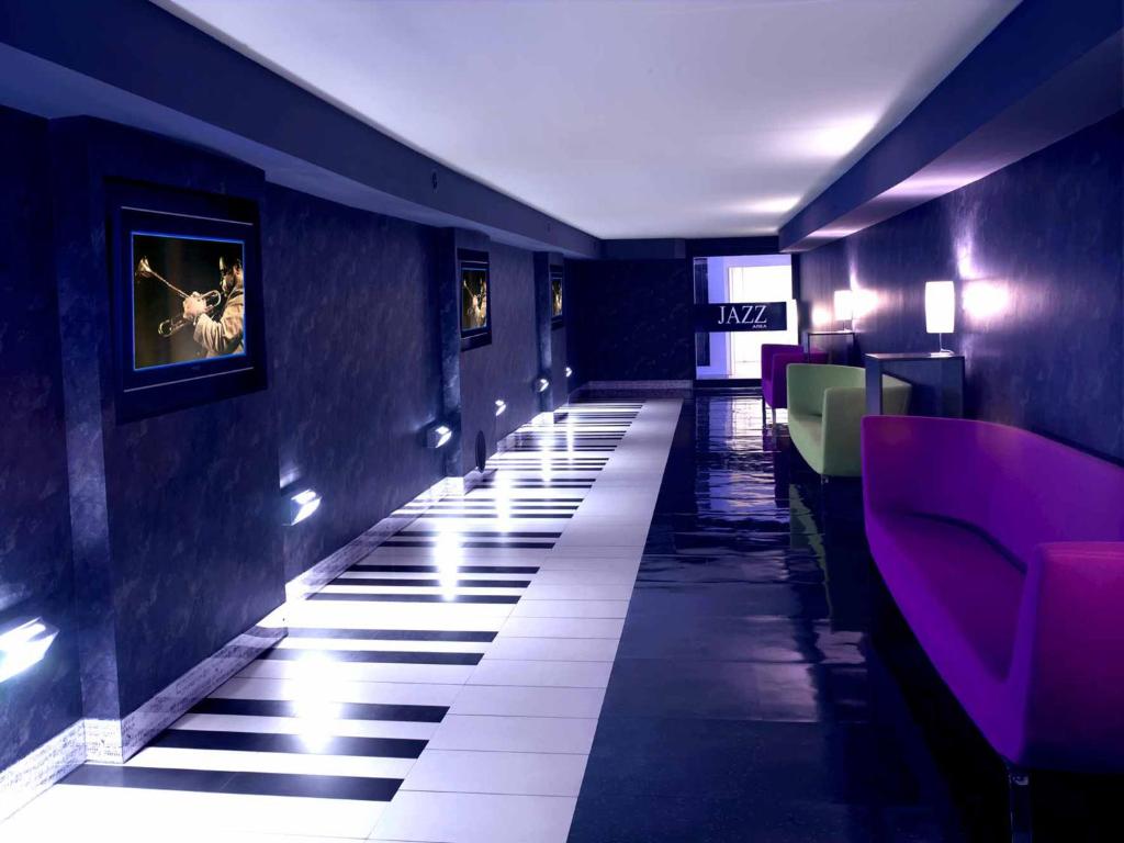 un couloir d'un restaurant aux murs violets et aux sols blancs dans l'établissement Hotel Giò Wine e Jazz Area, à Pérouse