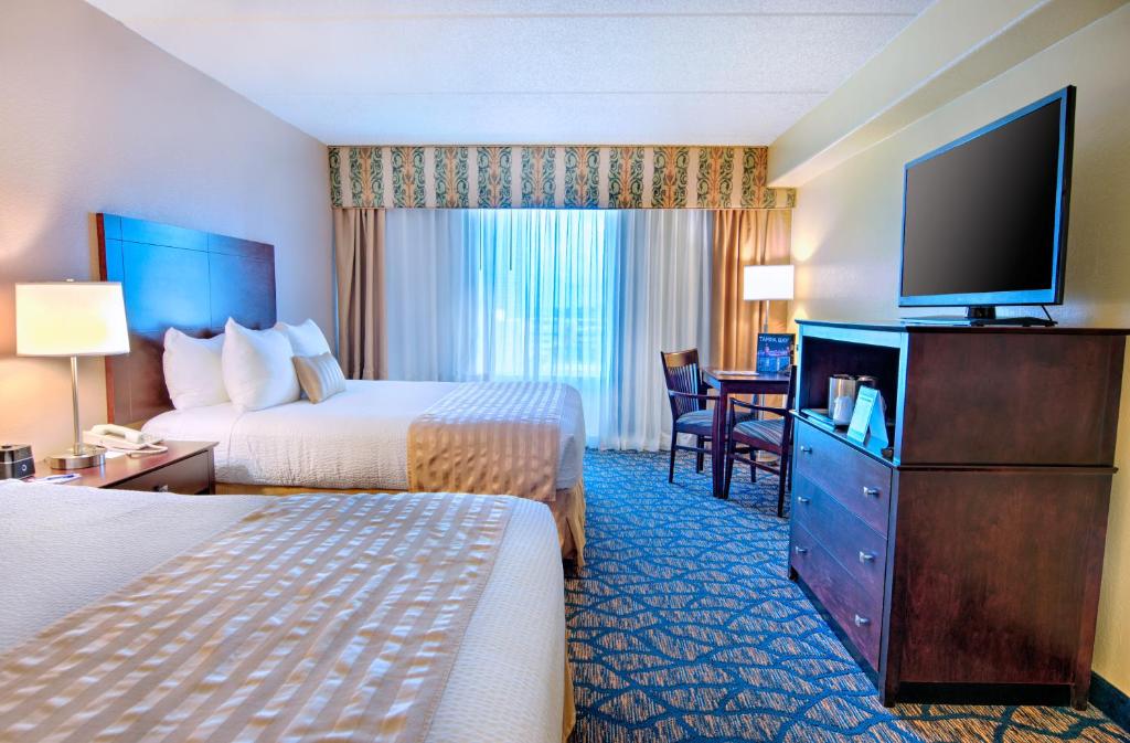 a hotel room with two beds and a flat screen tv at The Barrymore Hotel Tampa Riverwalk in Tampa