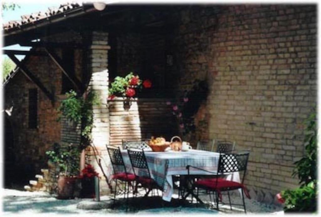 a table and chairs in a patio with a brick wall at Via S Cecilia 30 Urbania in Urbania