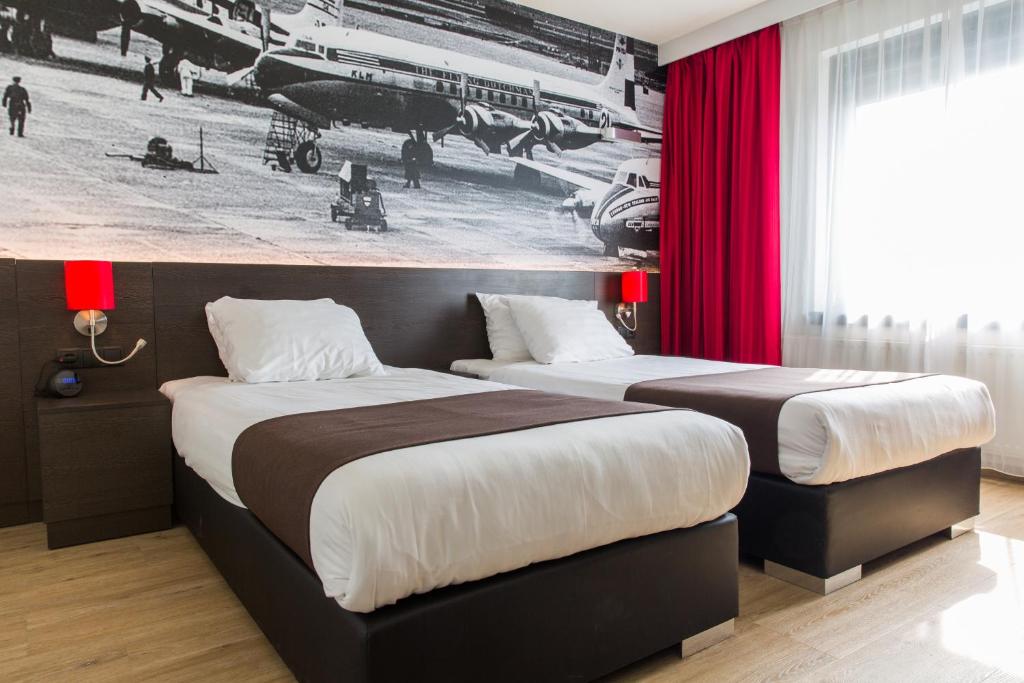 two beds in a hotel room with red curtains at Best Western Plus Amsterdam Airport Hotel in Hoofddorp