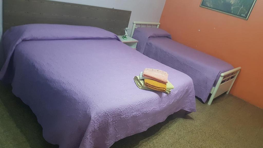 - une chambre avec 2 lits, des draps violets et des serviettes dans l'établissement B&B MIRAGLIA, à Naples