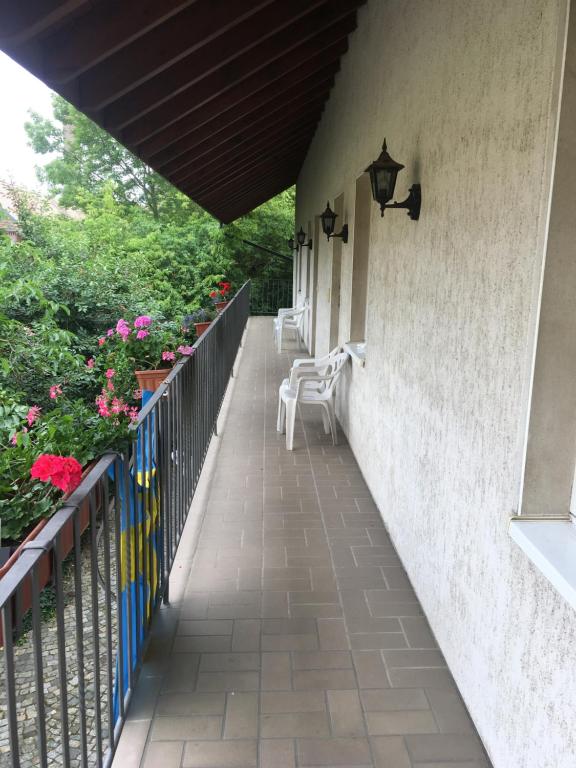 a porch with two white chairs and flowers at Landhotel Lützen-Stadt in Lützen