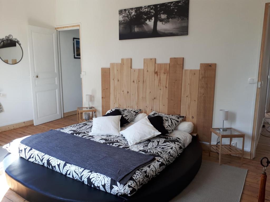 a bedroom with a large bed with a wooden headboard at Levaltipis in Saint Gatien des Bois