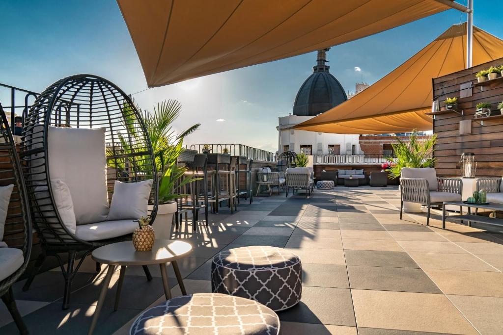 eine Terrasse mit Stühlen und Tischen auf dem Dach in der Unterkunft Vincci Vía - 66 in Madrid