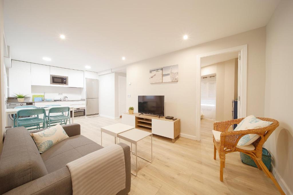 sala de estar con sofá y TV y cocina en Apartamento Centro-Nautico, en Gijón