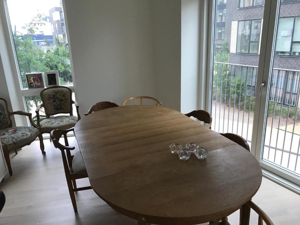 a wooden table in a room with chairs and a large window at Home Stay Marmormolen (Marmorvej) in Copenhagen