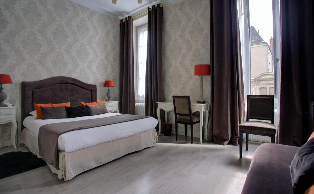 - une chambre avec un lit, une table et des chaises dans l'établissement Hôtel Du Mail, à Angers